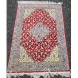 An Indian rug, the red field with a sky blue stepped medallion, ivory spandrels,