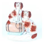 A Victorian Staffordshire group of two seated spaniels, one is on a barrel.