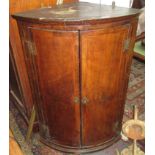 A Georgian inlaid walnut bow front corner cupboard, with a pair of doors enclosing four shelves,