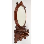 A mahogany oval wall mirror, above a gallery and rail, height 88cm, width 41cm.