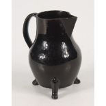 A Jackfield pottery jug, 18th century, on three feet, height 16cm, width 13cm.