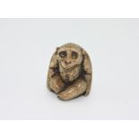 A bone netsuke carved as a monkey, early 20th century, height 3cm, width 2.4cm.