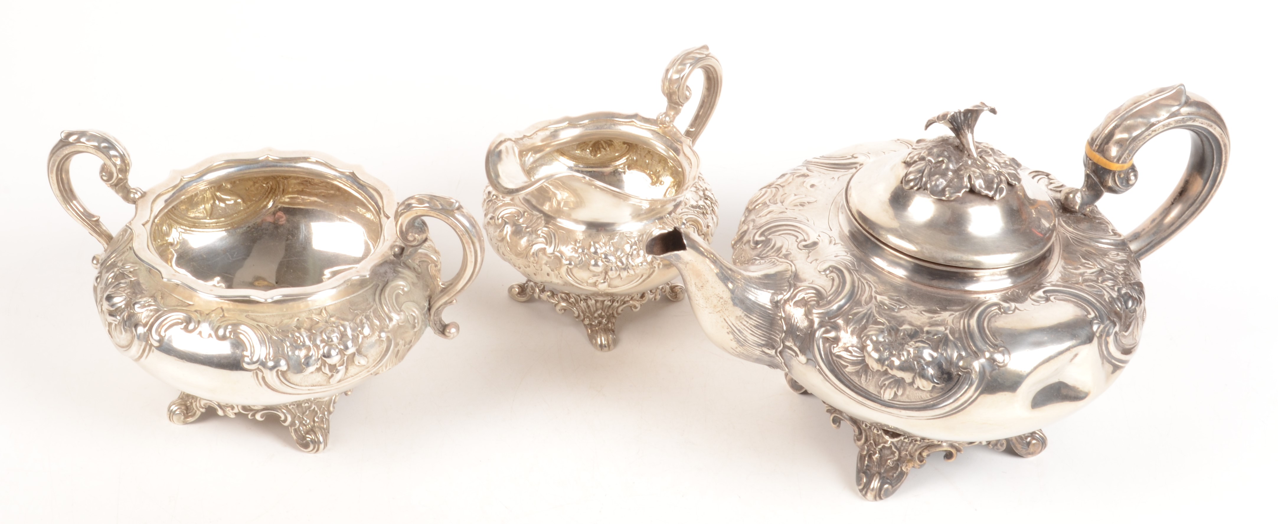 A ornate three piece silver service with floral and acanthus repousse decoration comprising a