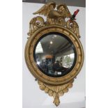 A gilt framed convex wall mirror, 19th century, surmounted by a carved eagle, diameter 64cm.