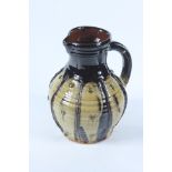 A Doug Fitch slipware jug, the ribbed body with a dark brown and celadon glaze, height 25cm.