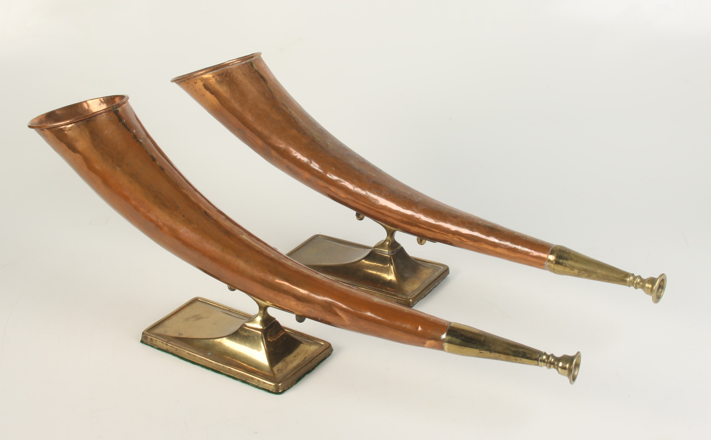 A pair of copper and brass hunting horns on stands, length 49cm.