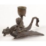 A bronze chamber candlestick, in the form of a goblin riding a dragon, height 10cm, length 16.5cm.