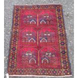 A Belouch rug, the madder field with six medallions enclosing stylised mosques,