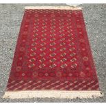 A Turkoman carpet, the deep red field with eleven rows of five octagonal medallions,