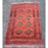 An Afghan rug, the burnt orange ground with four rows of two polychrome medallions,