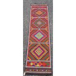 A kelim runner, with four polychrome diamond shaped medallions, 242 x 59cm.