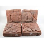 Four terracotta architectural tiles, one pair decorated with fruit and leaves, the other an urn,