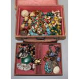 Costume jewellery in an old brown leather jewellery case.