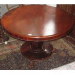 An early Victorian mahogany circular snap top table, the plinth base with three carved paw feet,