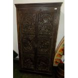An oak wardrobe, the moulded cornice above a pair of doors carved with Indian erotic scenes,
