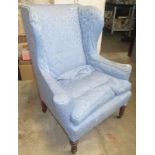 An upholstered wing armchair, 19th century, with oak turned and fluted, tapering front legs,