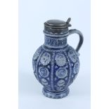 A German Westerwald stoneware jug, with white metal mounted hinged cover, height 25cm.
