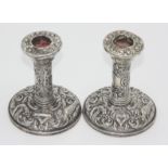 A pair of low filled silver candlesticks with bird and scroll repousse decoration.