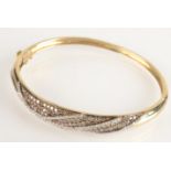 A 9ct gold modern French bangle set with white and champagne diamonds, 17.7g.