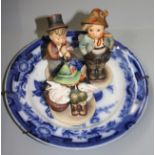 Three Hummel figures and a blue and white plate.