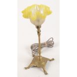 An Arts and Crafts brass adjustable table lamp, with a yellow flashed glass shade,