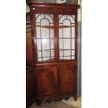 A George III mahogany standing corner cupboard, with a pair of glazed doors enclosing four shelves,