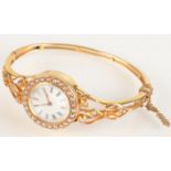 A high purity gold lady's hinged bangle wristwatch with pearl set bezel winding mechanism,