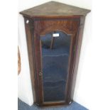 A late 19th century oak hanging corner display cabinet with glazed arched door and fluted column