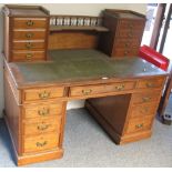 An Edwardian walnut double pedestal desk, the raised back having two banks of four drawers with