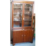 A reproduction mahogany glazed two-door bookcase on cupboard, with bevelled glass panels, 91cm wide,