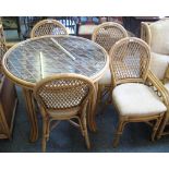 A cane conservatory dining suite comprising circular glass topped table and set of four matching