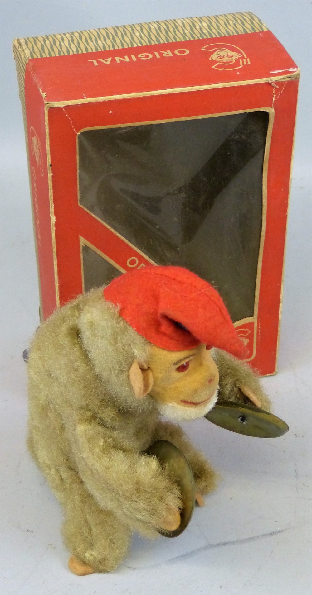 An Original West Germany plush covered clockwork figure of a monkey bandsman, seated playing the