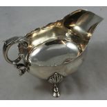 An Edwardian silver gravy boat, London 1906, with wavy border, leaf capped double scroll handle,