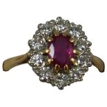 An 18ct gold ruby and diamond cluster ring, claw set with an oval mixed cut stone bordered by ten