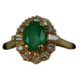 An 18ct gold emerald and diamond cluster ring, claw set with an oval mixed cut stone, bordered by