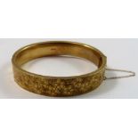 A 9ct gold hinged bangle, Birmingham 1968, the front panel with floral engraved decoration, weight