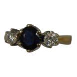 An 18ct gold sapphire and diamond three stone ring, claw set with an oval mixed cut stone flanked by