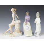 A Nao figure of a standing girl 27cm, a Nao figure of a girl with dog 24cm and a Nadal figure of a