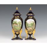 A pair of Sevres style gilt porcelain urns and covers with panelled decoration depicting country