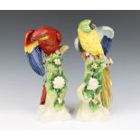 A pair of 20th Century Sitzendorf porcelain figures of parrots on rocky floral encrusted tree stumps