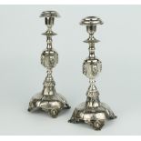 A pair of Continental repousse silver candlesticks with waisted stems decorated with masks on raised