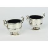 A pair of Edwardian silver table salts in the form of 2 handled trophies with blue glass liners