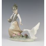 A Lladro figure group of a girl with a goose pecking her dress 21cm