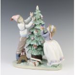 A Lladro group of a boy and a girl decorating a Christmas tree 5897, 29cm The star from the