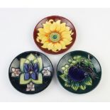 Three modern Moorcroft dishes, 1 with red ground decorated a sunflower, 1 green ground decorated