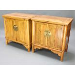 A near pair of Chinese light padauk cabinets enclosed by panelled doors, raised on square supports