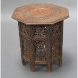 An Indian carved hardwood and inlaid brass octagonal folding occasional table raised on a pierced