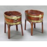 A pair of George III oval coopered mahogany wine coolers with brass banding and lion mask handles,