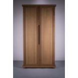 AN UPRIGHT OAK TWO DOOR WARDROBE, BY PHI