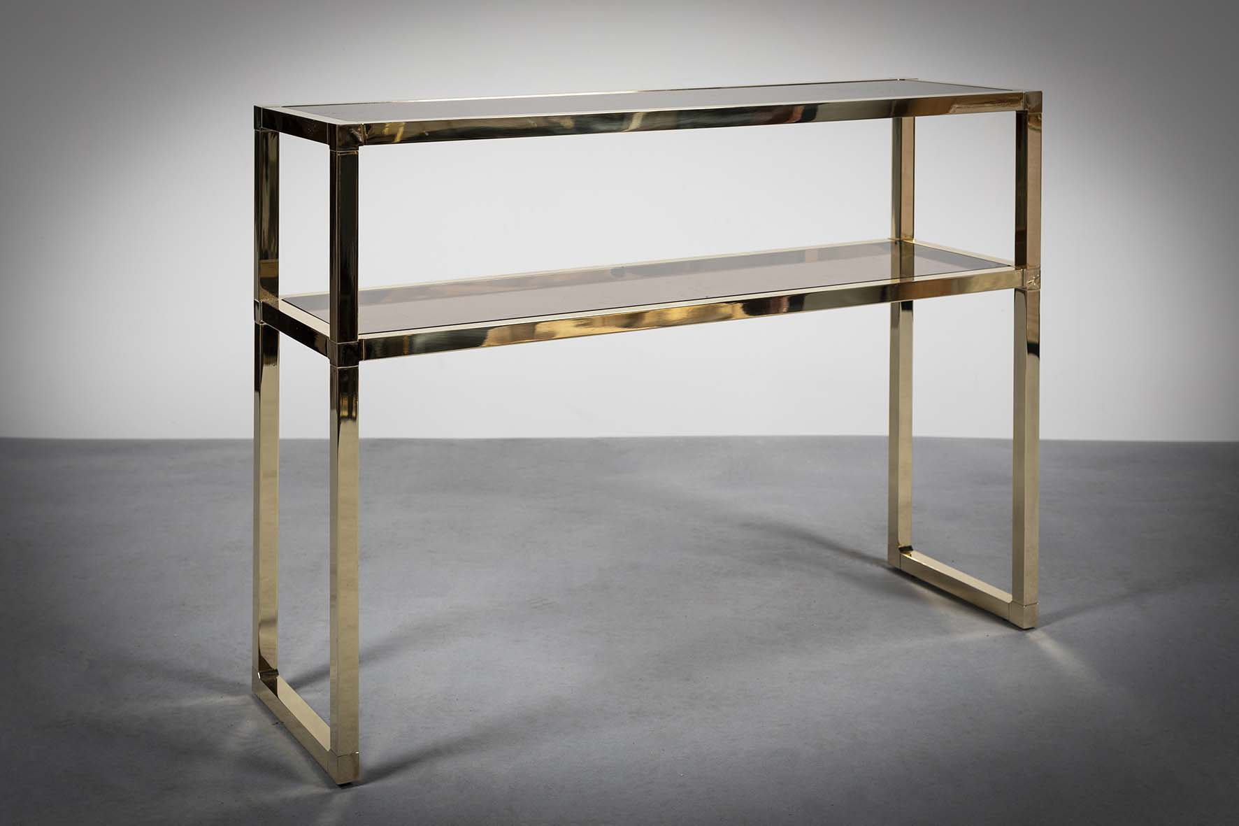 A GILT METAL TWO TIER CONSOLE TABLE, 1970s, with bronzed mirrored shelves, 100cm (w) x 30cm (d) x